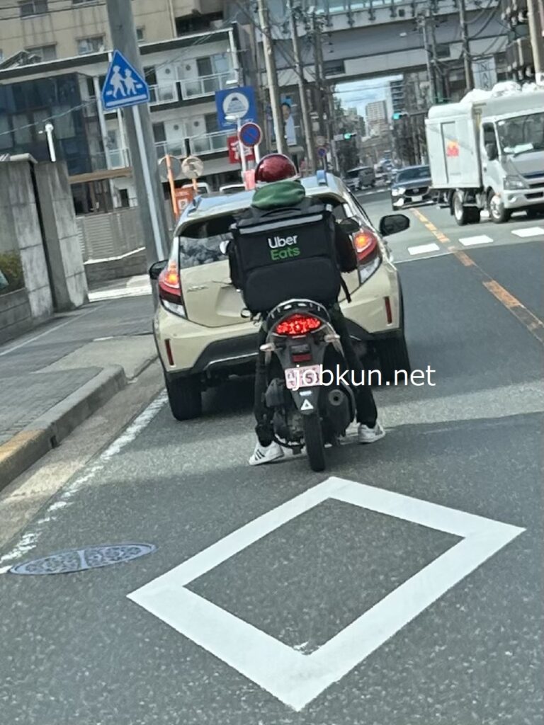 バイクで注文品を配達するウーバーイーツの配達員